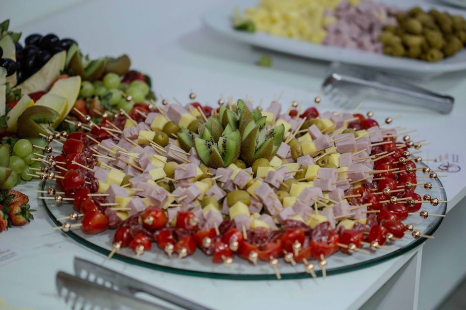 Vibrant platter of fruit and cheese skewers with kiwi, olives, and tomatoes.