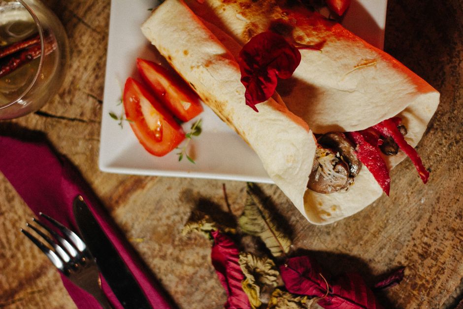 Gourmet vegan wrap served with fresh tomato slices.